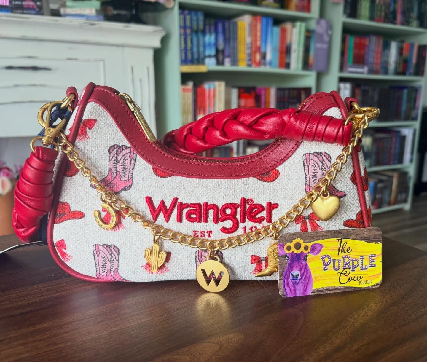 A donated Wrangler purse, a Book Lotería prize from The Purple Cow Boutique, in front of the shelves.